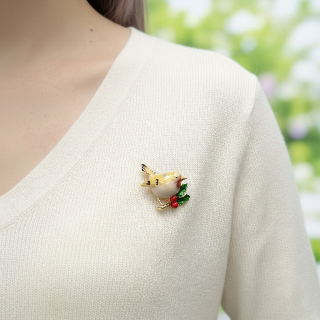 Bird-shaped brooch on a person wearing a white sweater with a blurred green background