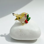 Decorative bird figurine with red berries on a white stone surface