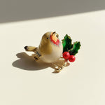 Decorative figurine of a bird with holly leaves and berries on a light background