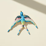 Decorative bird figurine with colorful feathers and gemstones on a beige background