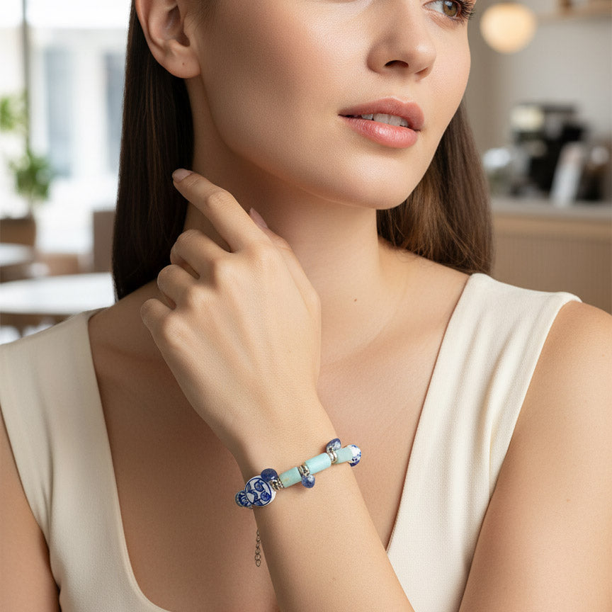Woman wearing a blue and silver bracelet in a blurred indoor setting