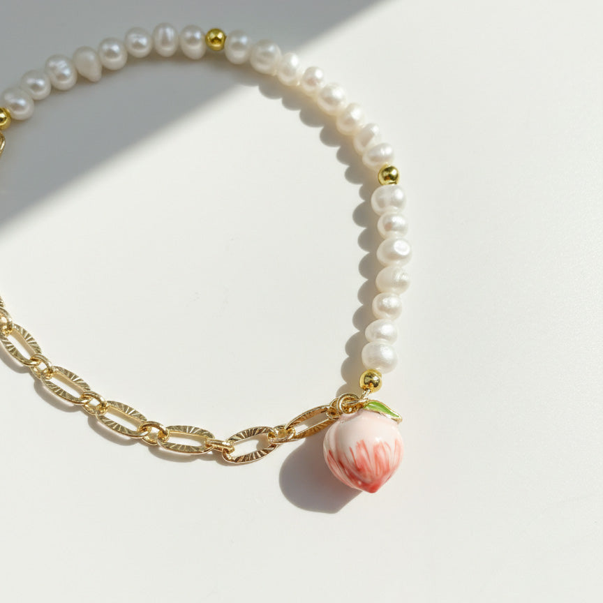 Close-up of peach enamel charm on freshwater pearl bracelet