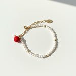Freshwater pearl bracelet with hand-painted red apple charm in 18K gold-plated brass on a white background
