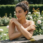 Model wearing freshwater pearl bracelet with pavé pomegranate charm and greenery in the background