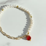 Close-up of pavé pomegranate charm with cubic zirconia on pearl bracelet