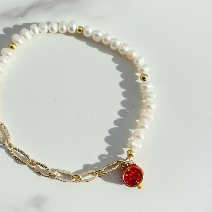 Close-up of pavé pomegranate charm with cubic zirconia on pearl bracelet