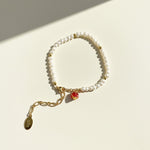 pavé pomegranate charm with cubic zirconia on pearl bracelet on a light background