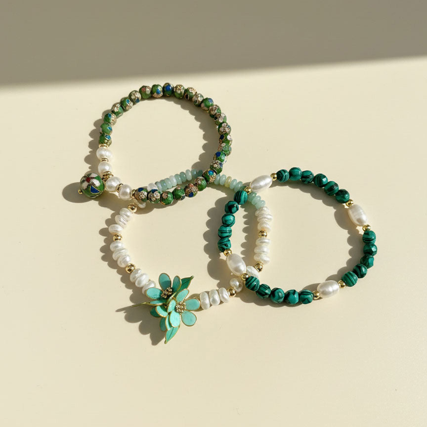 Three beaded bracelets with green and white stones on a beige background