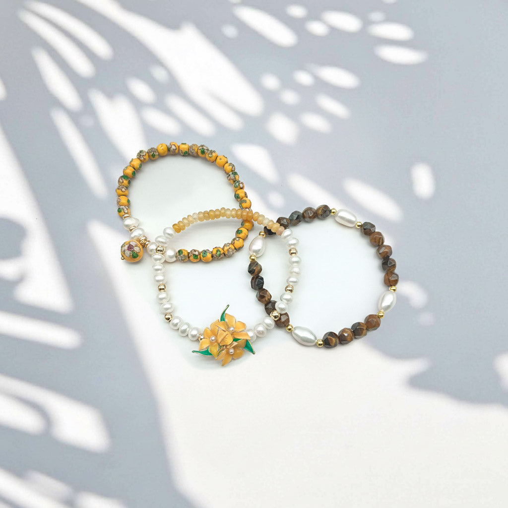 yellow-opal-tiger-eye-floral-bracelet-set on a light gray surface with leaf shadows