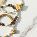 Close-up of handcrafted yellow resin flower with pearls and tiger eye beads on a marble surface