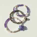 Layered amethyst freshwater pearl and cloisonné bracelet set on a light background