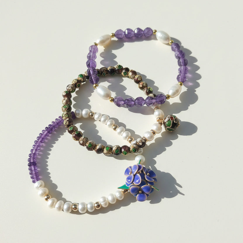 Layered amethyst freshwater pearl and cloisonné bracelet set on a light background