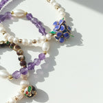 Close-up of purple handcrafted resin flower with amethyst beads on a white surface