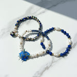 blue resin flower charm with lapis and pearl beads on a marble surface