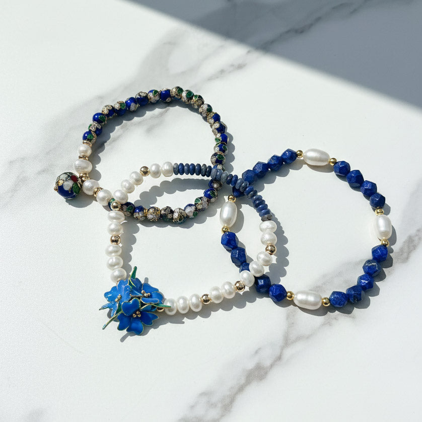 blue resin flower charm with lapis and pearl beads on a marble surface