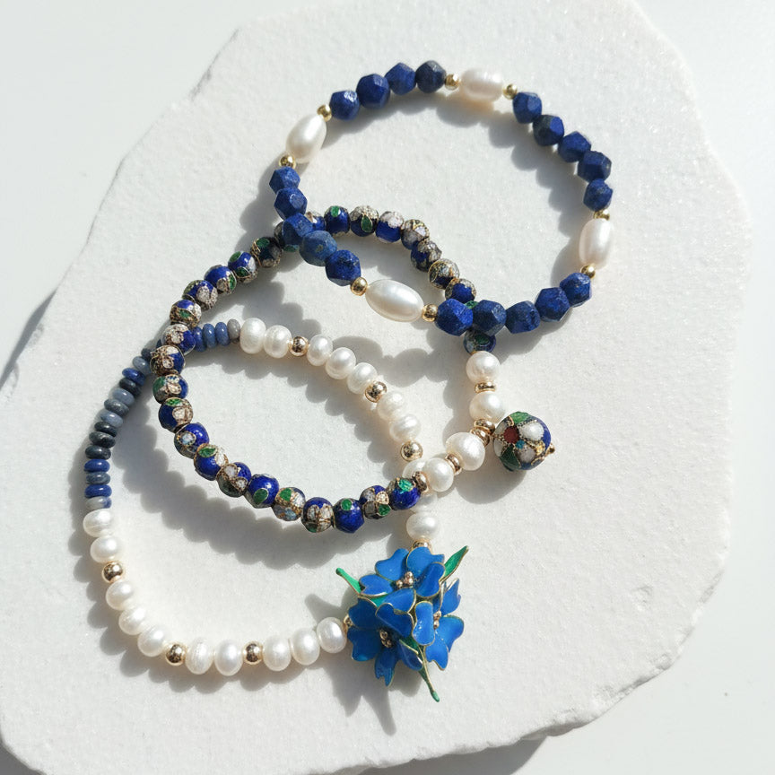 Sodalite and lapis floral beaded bracelet set with freshwater pearls on a white stone surface