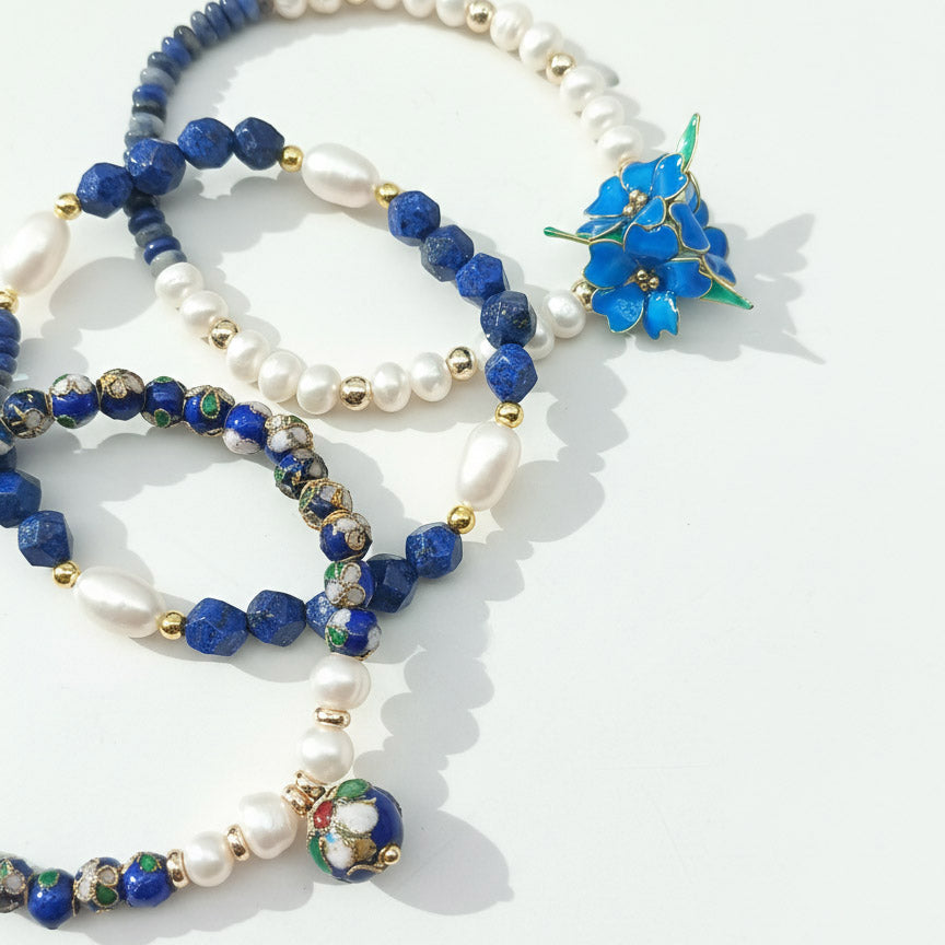 Close-up of blue resin flower charm with lapis and pearl beads on a white background