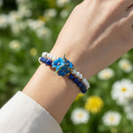 sodalite lapis and cloisonné beaded bracelet set on a wrist against a blurred floral background