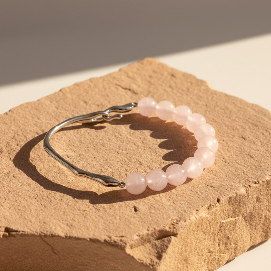 8mm Rose Quartz bracelet with stainless steel hook on natural stone background in warm sunlight