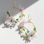 Floral hoop earrings with pink flowers and green leaves on a light background