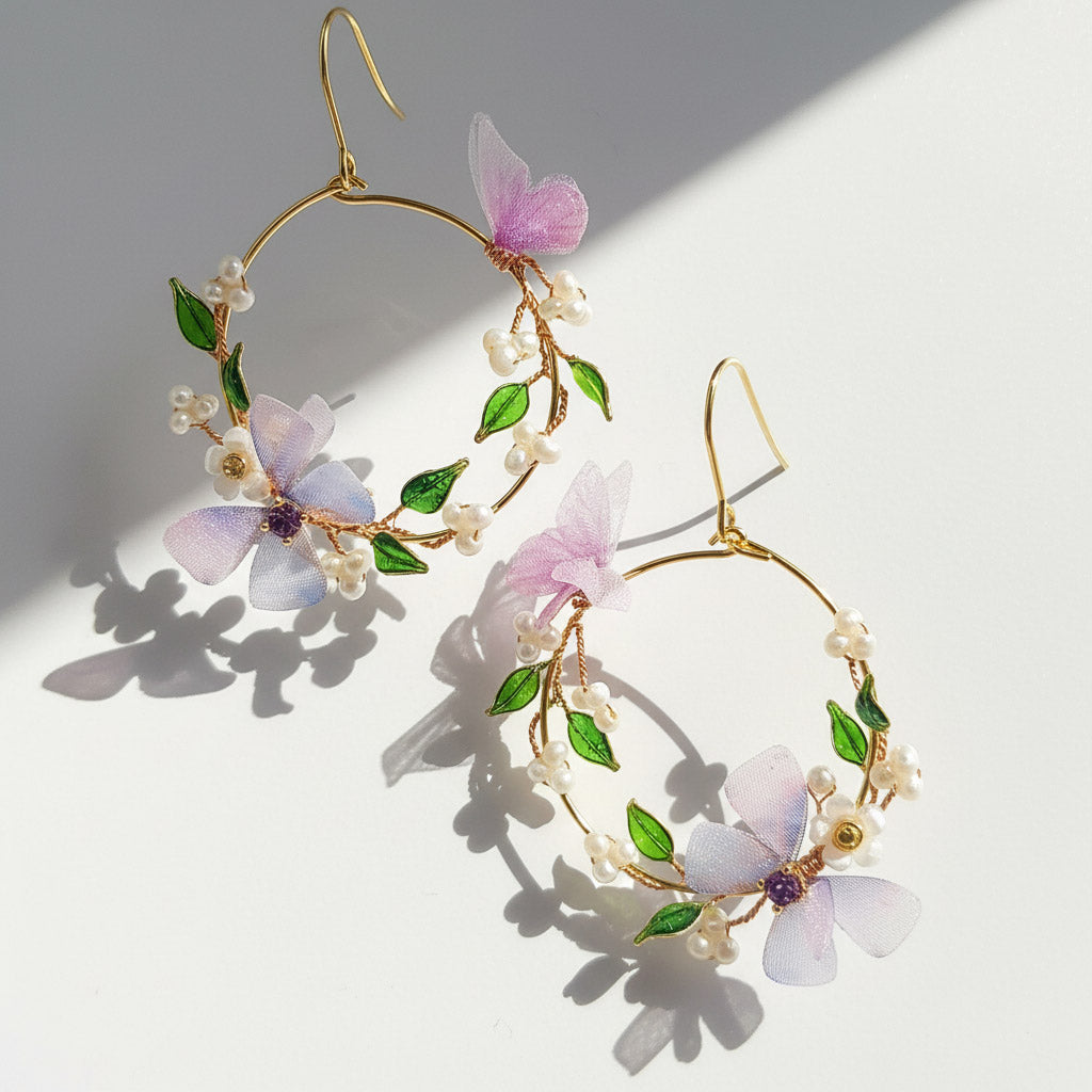 Floral hoop earrings with pink flowers and green leaves on a light background