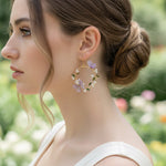 Woman wearing floral hoop earrings with a blurred garden background