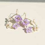Elegant earrings with purple flowers and pearl accents on a light background