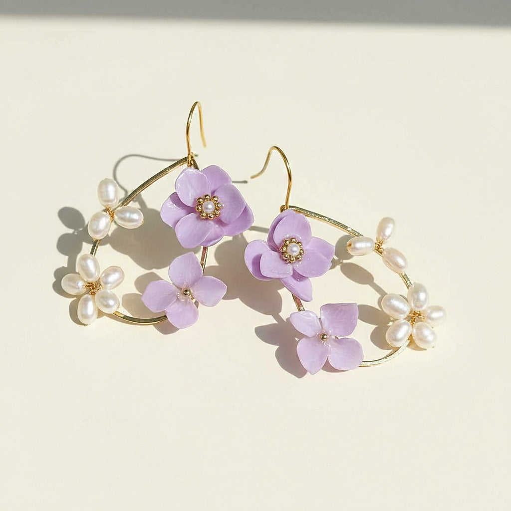 Elegant earrings with purple flowers and pearl accents on a light background