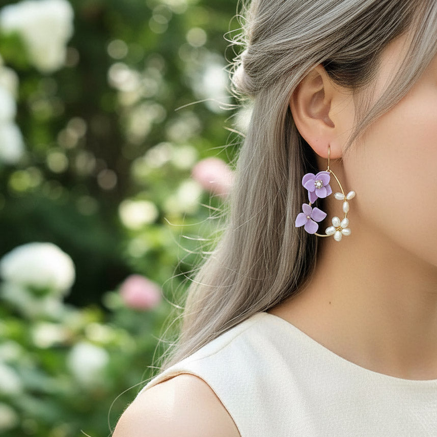 Person wearing a floral earring with a blurred garden background