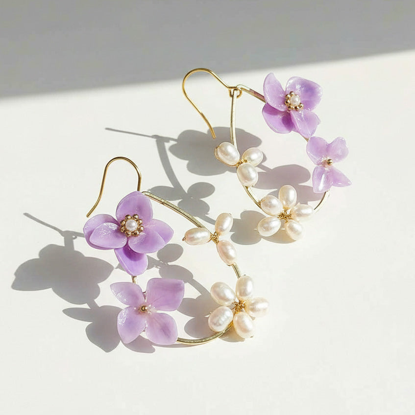 Floral earrings with purple flowers and pearl-like centers on a light background