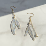 Pair of earrings with wing-like design on a light background