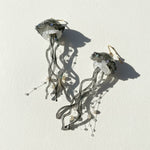 Jellyfish-shaped earrings with crystal-like bodies on a white background