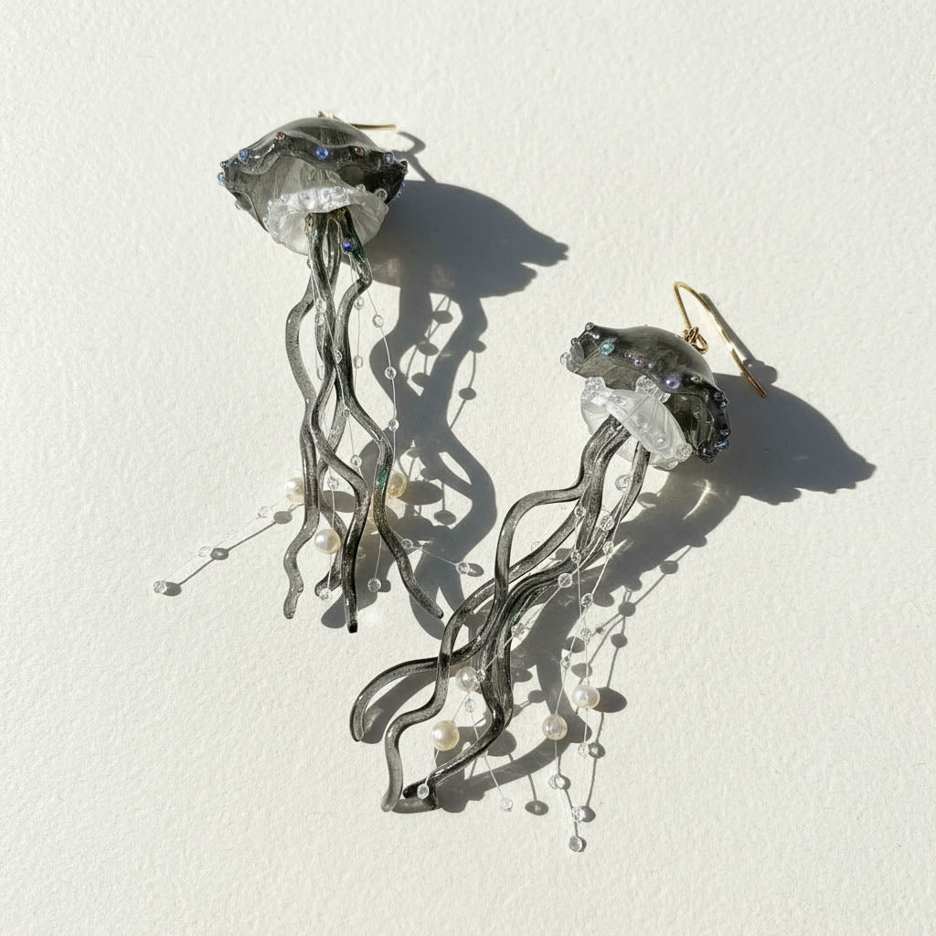 Jellyfish-shaped earrings with crystal-like bodies on a white background