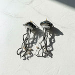 Jellyfish-shaped earrings on a textured white surface