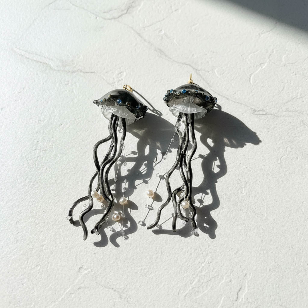 Jellyfish-shaped earrings on a textured white surface