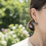 Close-up of a person wearing an earring with a blurred natural background