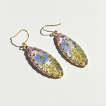 Teardrop-shaped earrings with floral design on a light background