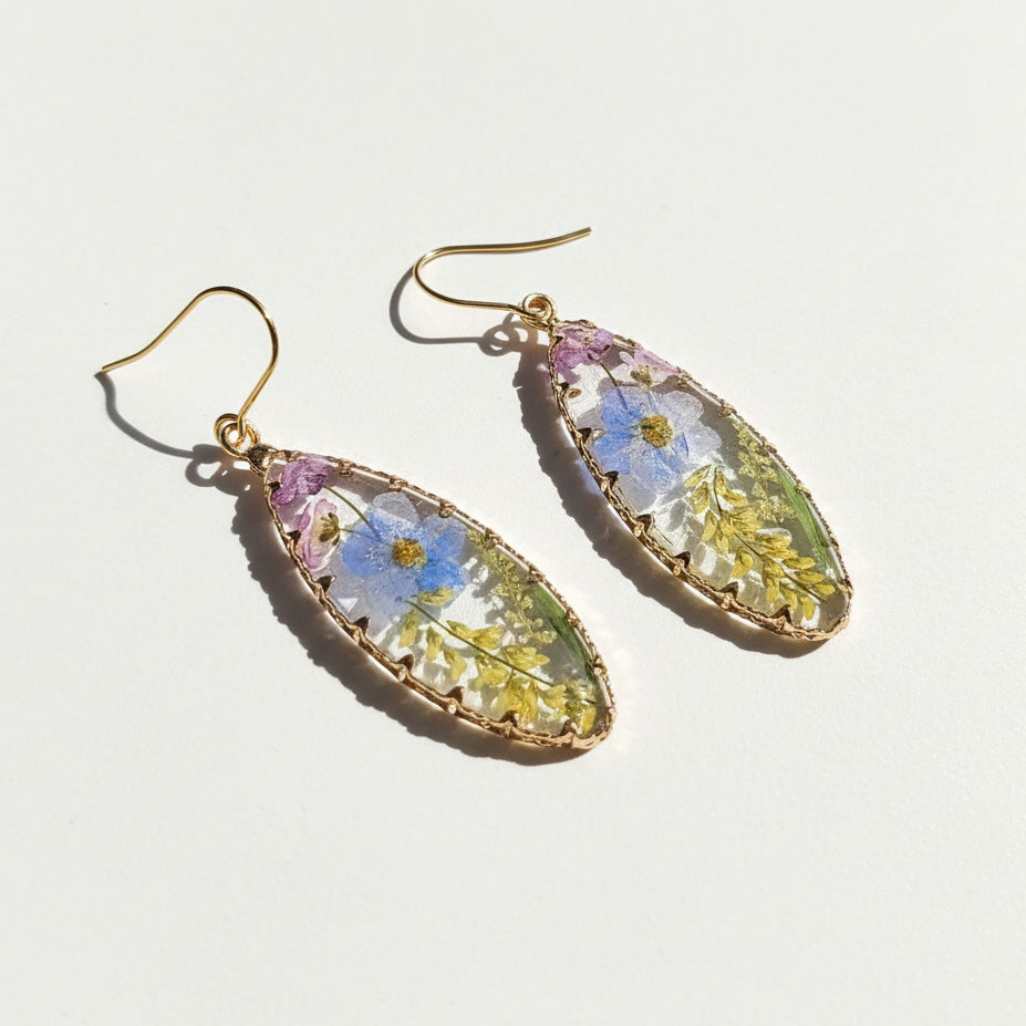 Teardrop-shaped earrings with floral design on a light background