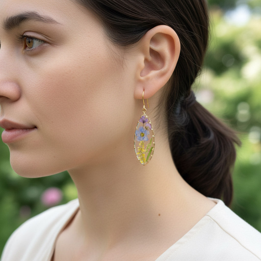 Close-up of a woman wearing floral earrings with a blurred green background