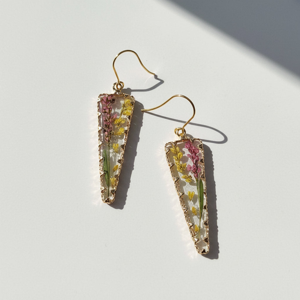 Trapezoid-shaped earrings with floral embedded stones on a white background