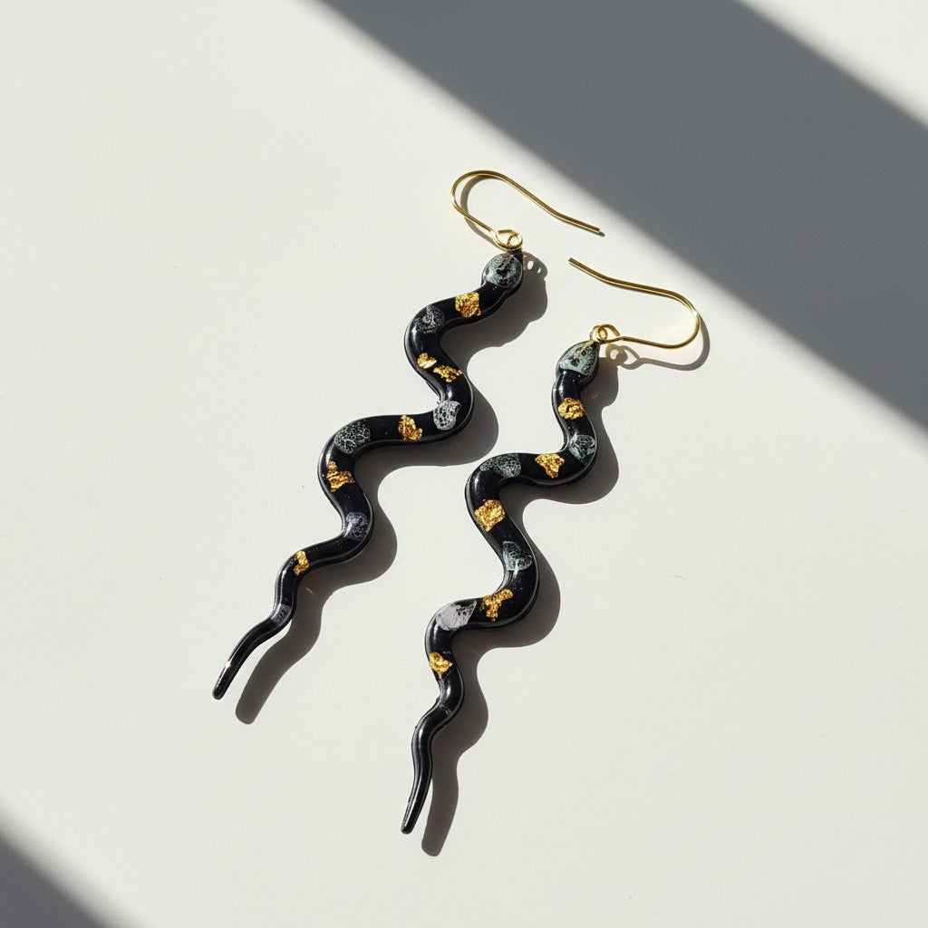 Serpentine earrings with gold accents on a light background