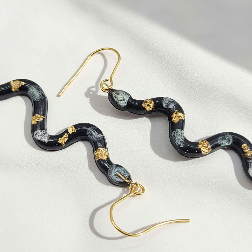 Snake-shaped earrings with gold accents on a light background