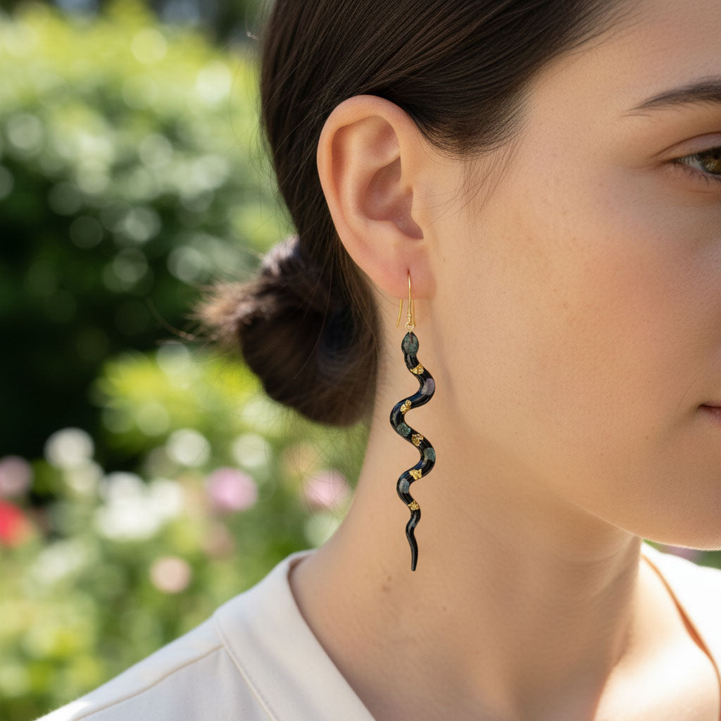 Woman wearing a black and gold spiral earring with a blurred garden background