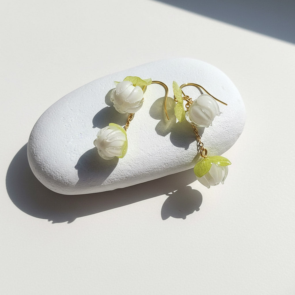 Floral earrings on a white stone with sunlight casting shadows
