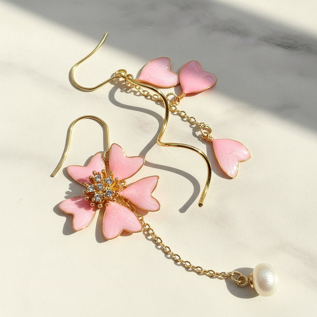 Pink flower-shaped earrings with gold chains on a light background