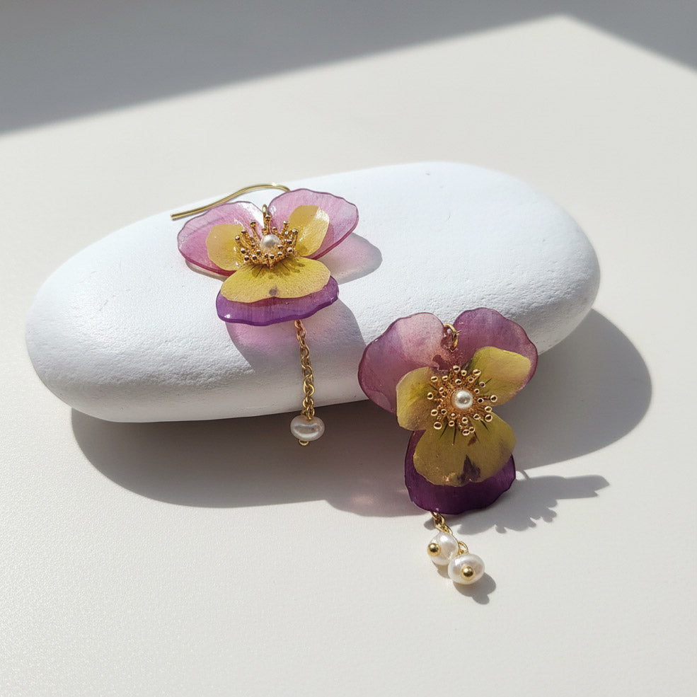 Floral earrings with purple and yellow flowers on a white stone
