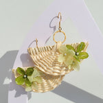 Woven earrings with floral details on a light background