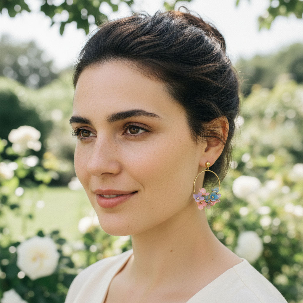 Woman wearing floral hoop earrings with a blurred garden background