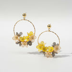 Gold hoop earrings with floral elements on a light gray background