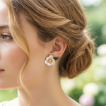Close-up of a woman wearing a floral earring with a blurred green background